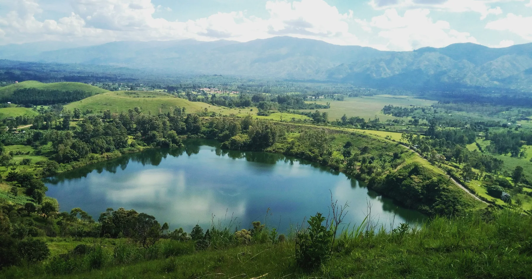 A crater lake surrounded by green hills in Uganda